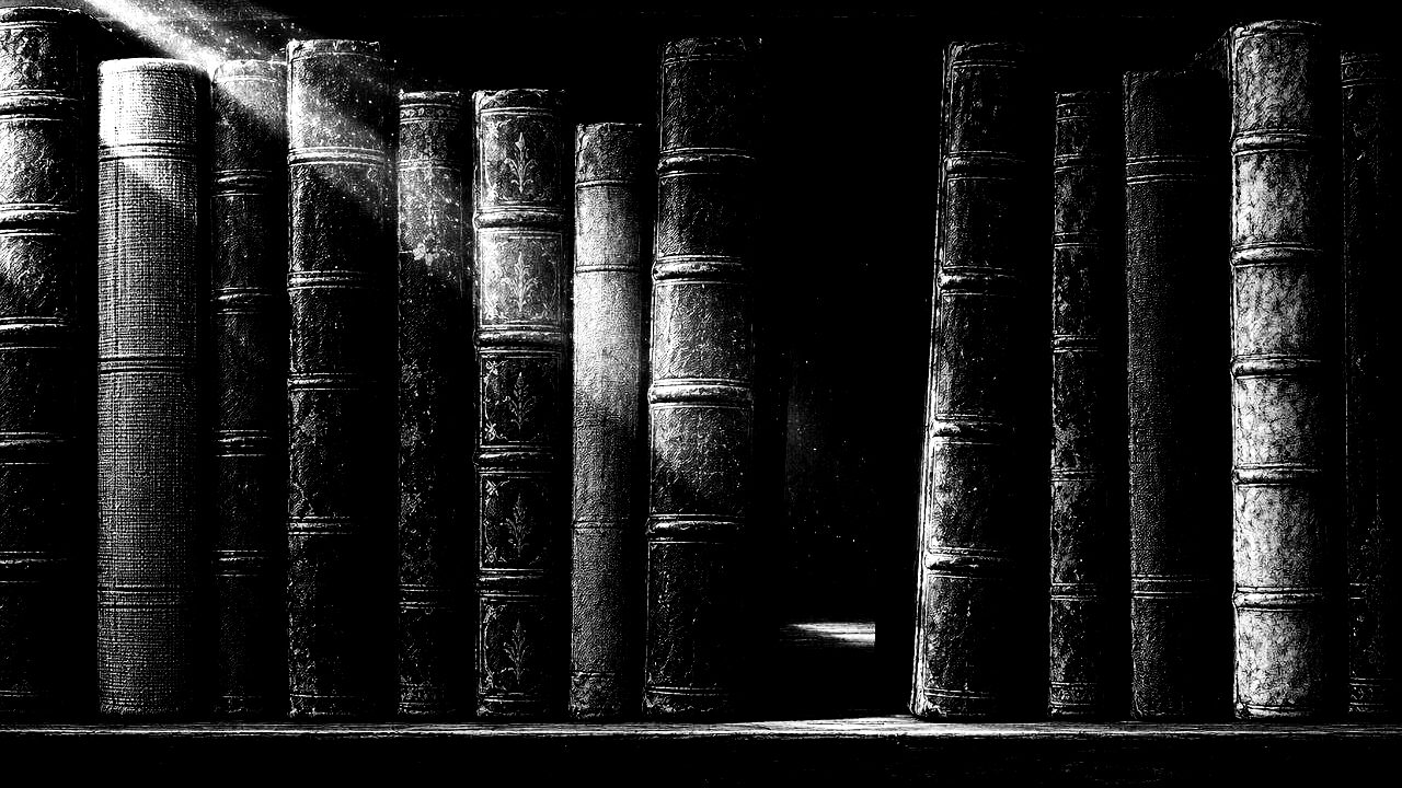 Lomos de libros antiguos vistos de frente, con un hueco en medio y polvo suspendido en un haz de luz